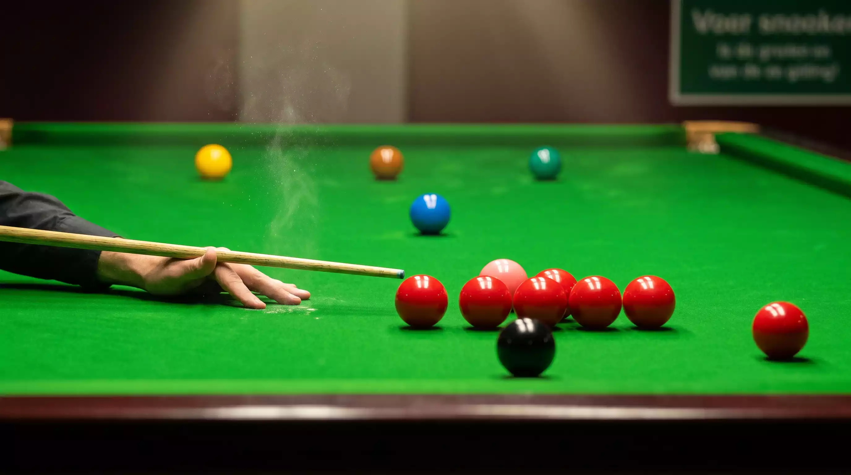 Close-up van snookerballen in driehoeksformatie op groen laken met keu
